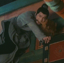 a man is laying on the floor with his head on a table and looking down at something .