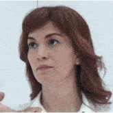 a woman with red hair wearing a white shirt and earrings