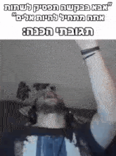 a man with a beard and headphones is sitting on a couch with his arms up in the air .