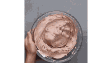 a person is mixing chocolate whipped cream in a glass bowl .