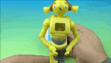 a person is holding a yellow toy that looks like shrek 's mother