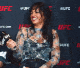a woman laughing in front of a ufc banner