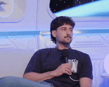 a man sitting on a couch with a microphone and a shirt that says bluet on it
