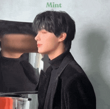 a man in a black suit is standing in front of a mirror with the word mint on the bottom