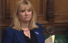 a woman in a blue jacket with a purple horse pin on her jacket