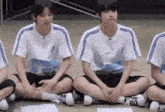 a group of young men are sitting on the floor with their feet crossed .