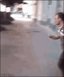 a man is walking down a street while looking at his cell phone
