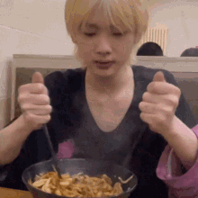 a young man is eating a bowl of food with a fork