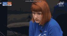 a woman with red hair is wearing a blue shirt with the word fiddy on it