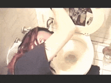 a woman with red hair is sitting on a toilet with her head in the toilet