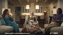 three women are sitting on a couch in a living room with a nbc logo on the bottom
