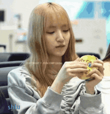 a girl with long blonde hair is holding a yellow toy with a face on it .