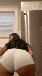 a woman in white shorts is dancing in a kitchen .