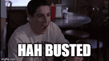 a man is sitting at a table with the words " hah busted " written on it
