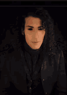 a man with long curly hair is wearing a black shirt