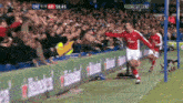 a soccer player celebrates a goal in front of a crowd with sky sports live in the background