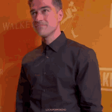 a man in a black shirt stands in front of a wall that says walker on it