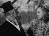 a man in a top hat is talking to a woman in a leopard print coat