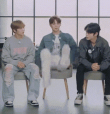a group of young men are sitting on chairs in a room .