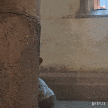 a stuffed animal with antlers is peeking out from behind a stone wall with a netflix logo on the bottom