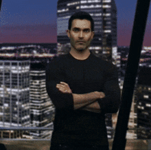 a man in a black shirt is standing with his arms crossed in front of a city skyline