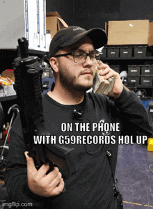 a man holding a gun and talking on a cell phone