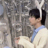 a man wearing bunny ears and a sweater is standing in front of balloons .