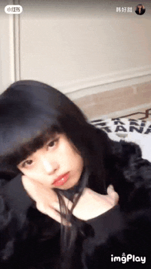 a woman with long black hair is sitting on a bed .
