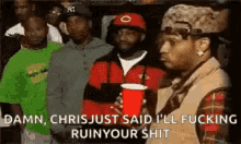 a group of men are standing next to each other in a room . one of the men is holding a red cup .