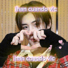 a young man in a plaid shirt is making a heart with his hands .