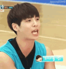 a young man in a blue tank top is making a face