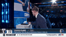 a man in a suit stands in front of a screen with the name cooper on it