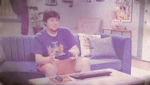 a man sits on a blue couch playing a video game