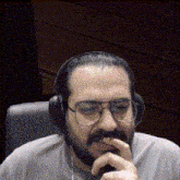 a man with a beard and glasses wearing headphones and a grey shirt