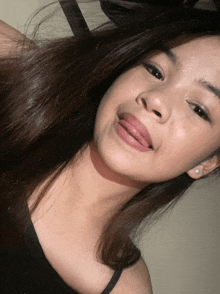 a girl with her tongue out and a black tank top on