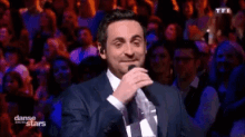 a man in a suit singing into a microphone with danse des stars written on the bottom