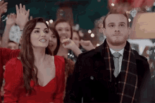 a man and a woman are standing next to each other in front of a crowd of people at a party .