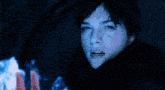 a woman in a dark room with a blue light coming out of her hand