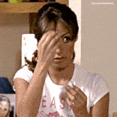 a woman wearing a t-shirt that says easy wipes her face