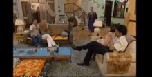 a man is sitting on a couch in a living room with other people