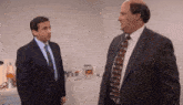 two men in suits and ties are standing next to each other in a room