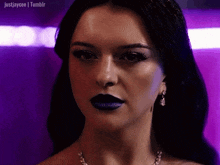 a woman wearing purple lipstick and earrings looks at the camera .