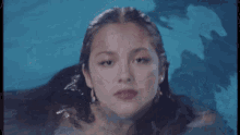 a woman is swimming in a pool with her eyes closed and her hair floating in the water .
