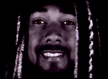 a close up of a man 's face with dreadlocks smiling