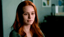 a woman with red hair and a tattoo on her forehead is looking at the camera .
