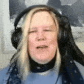a woman wearing headphones and a scarf is sitting in front of a computer .