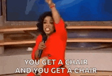 a woman in a red dress is holding a microphone and says you get a chair and you get a chair