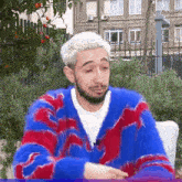 a man with white hair and a beard is wearing a blue and red furry sweater