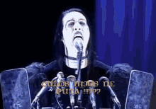 a man is speaking into a microphone with the words " culos hijos de puta " written in yellow