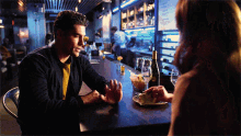 a man and a woman are sitting at a bar with a bottle of wine